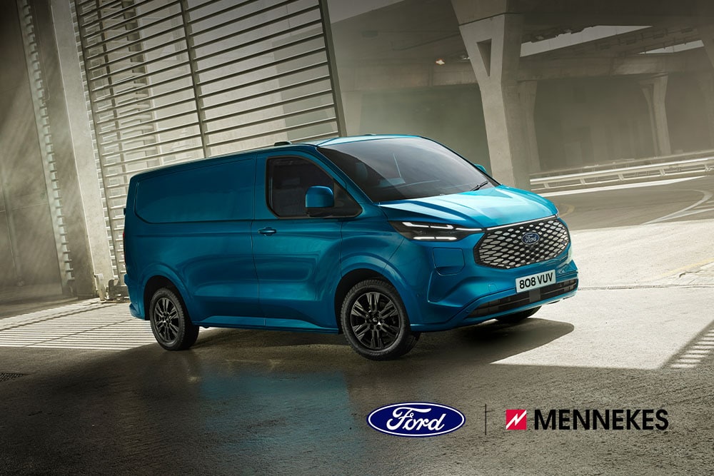 Un Ford E-Transit Custom blu visto da un'angolazione anteriore di tre quarti, parcheggiato sotto un ponte.