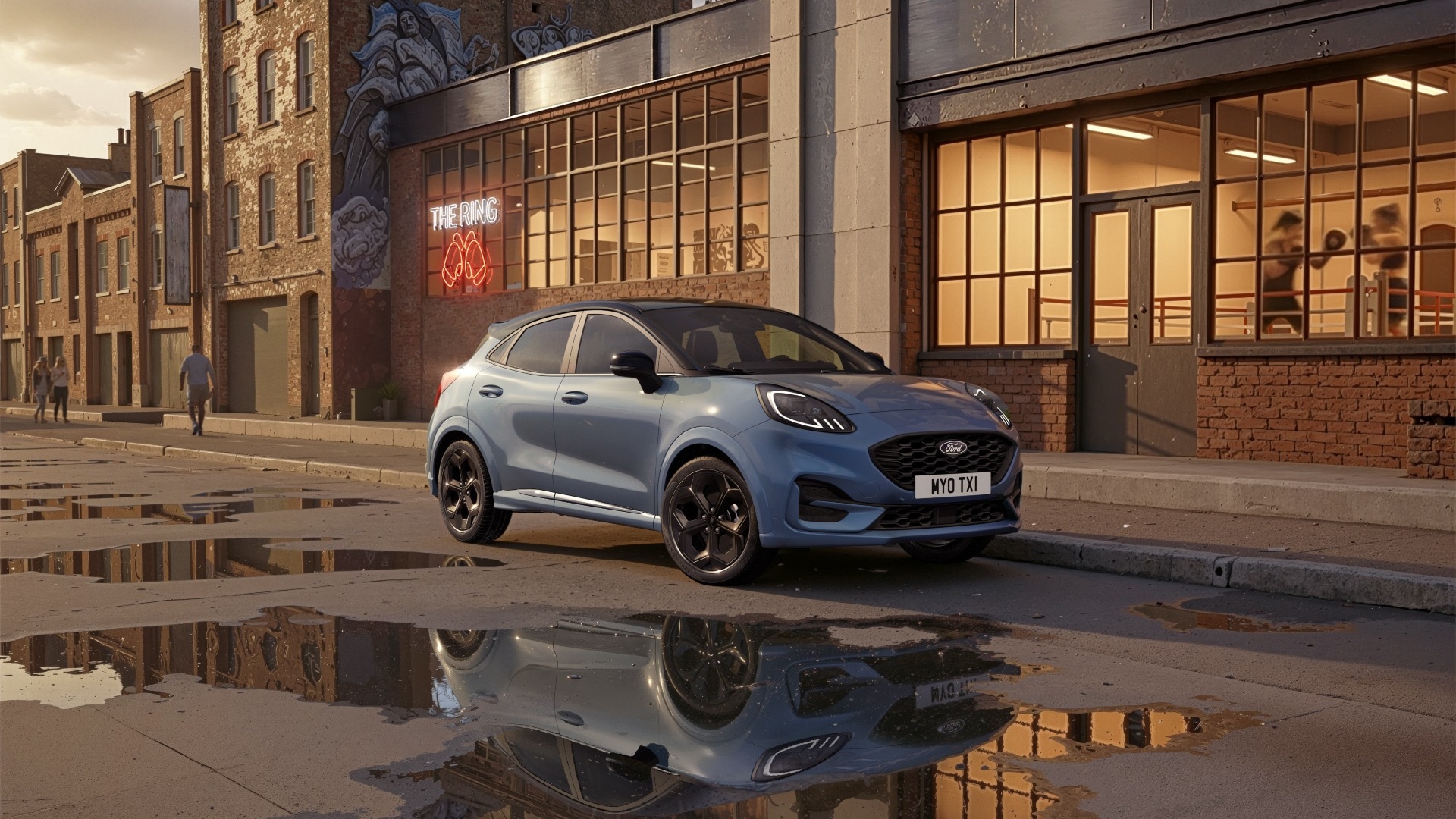 Una Ford Puma blu è parcheggiata su una strada cittadina bagnata con riflessi nelle pozzanghere.