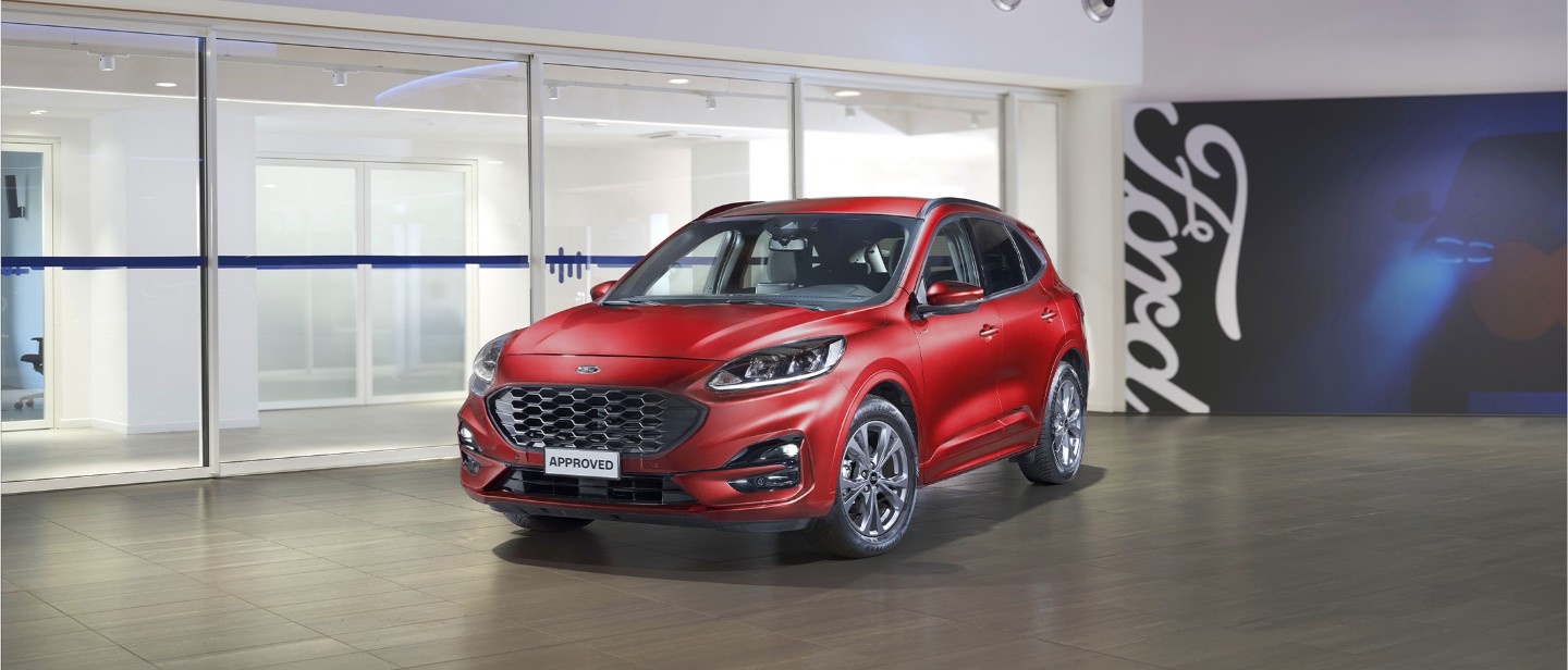 Kuga parcheggiata con logo Ford in secondo piano.