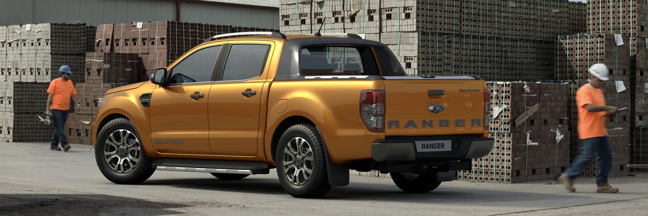 Rear shot of an orange Ford Ranger Wildtrak parked at a building site with two workers