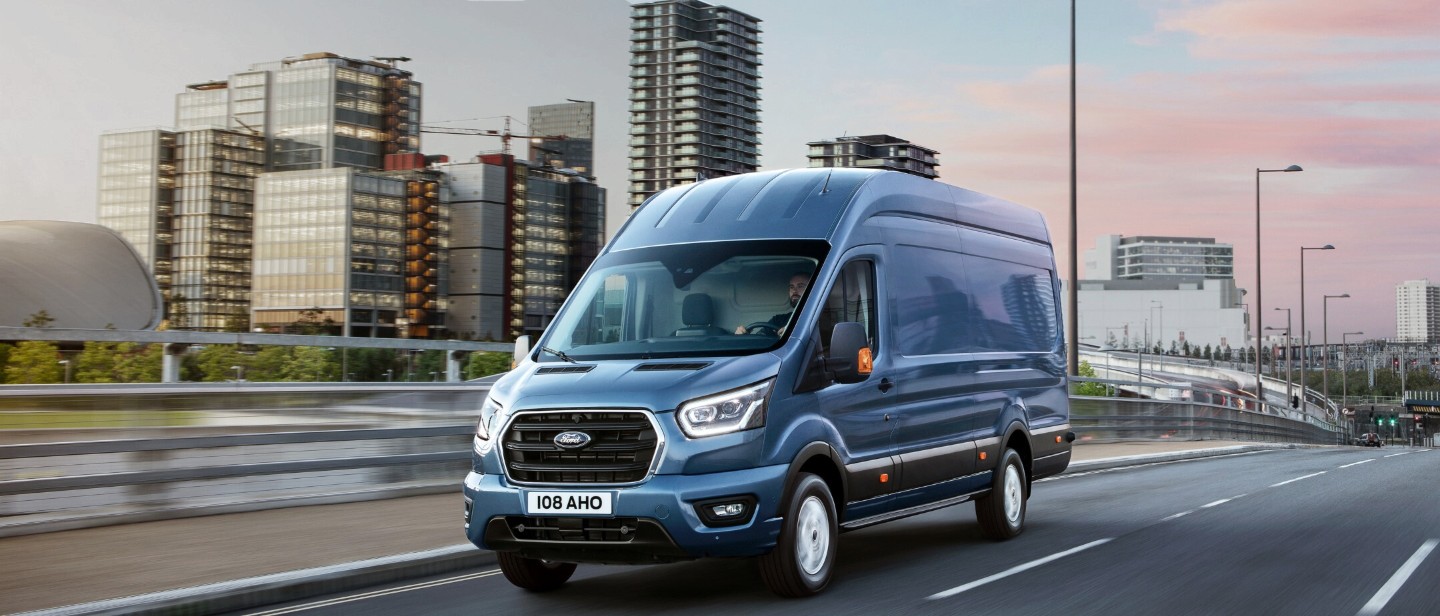 Furgone Ford Transit blu che guida su una strada cittadina