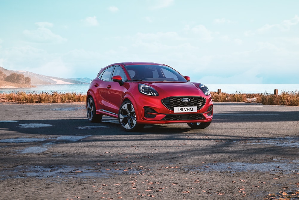 Puma rossa parcheggiata in primo piano su sterrato.