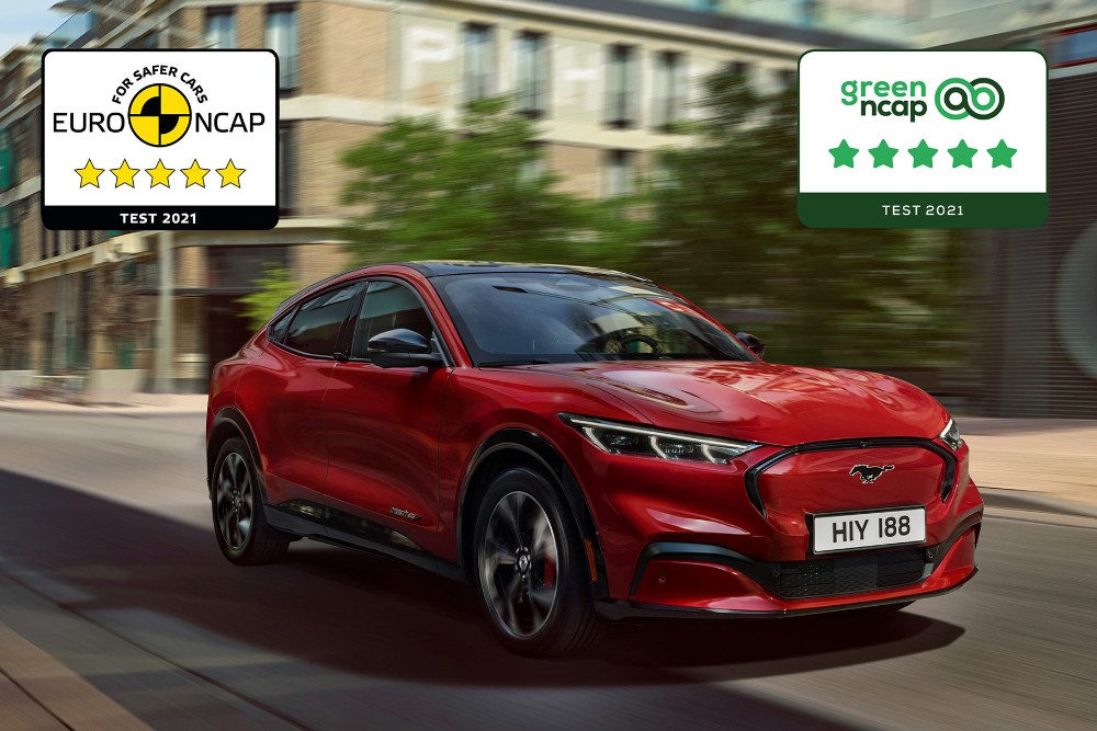 Una Mustang Mach-E rossa che percorre una strada con i loghi dei premi di sicurezza NCAP sovrapposti.