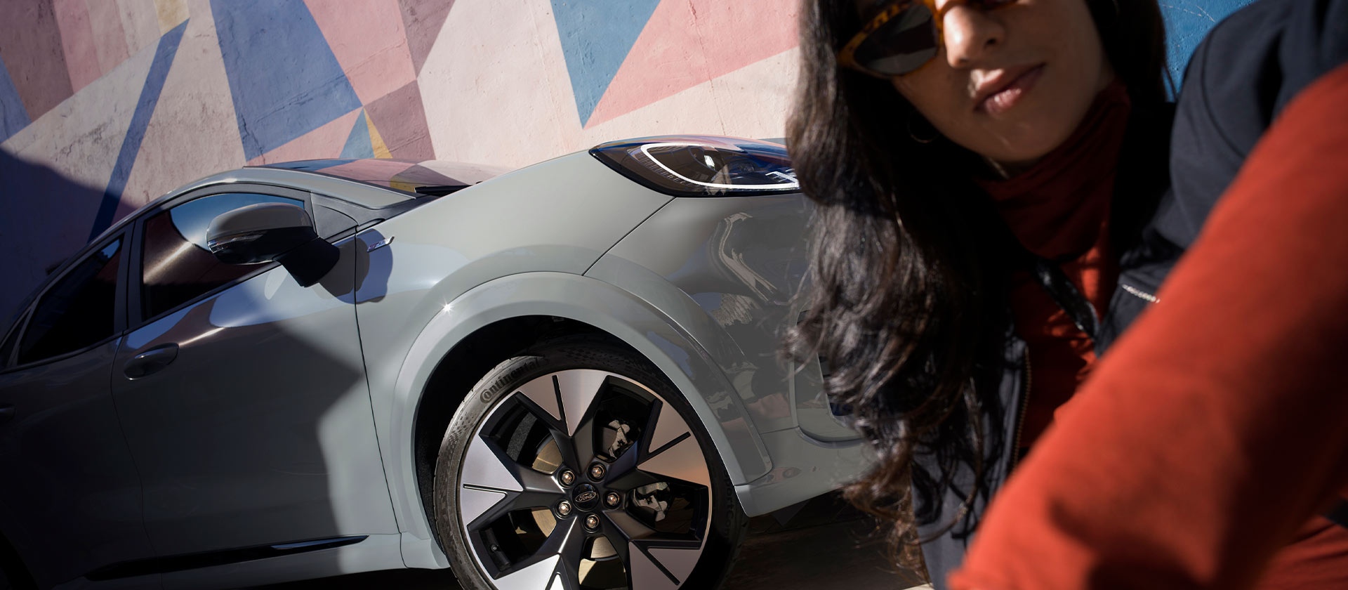 Una persona seduta accanto a una Ford Puma Mild Hybrid silver.