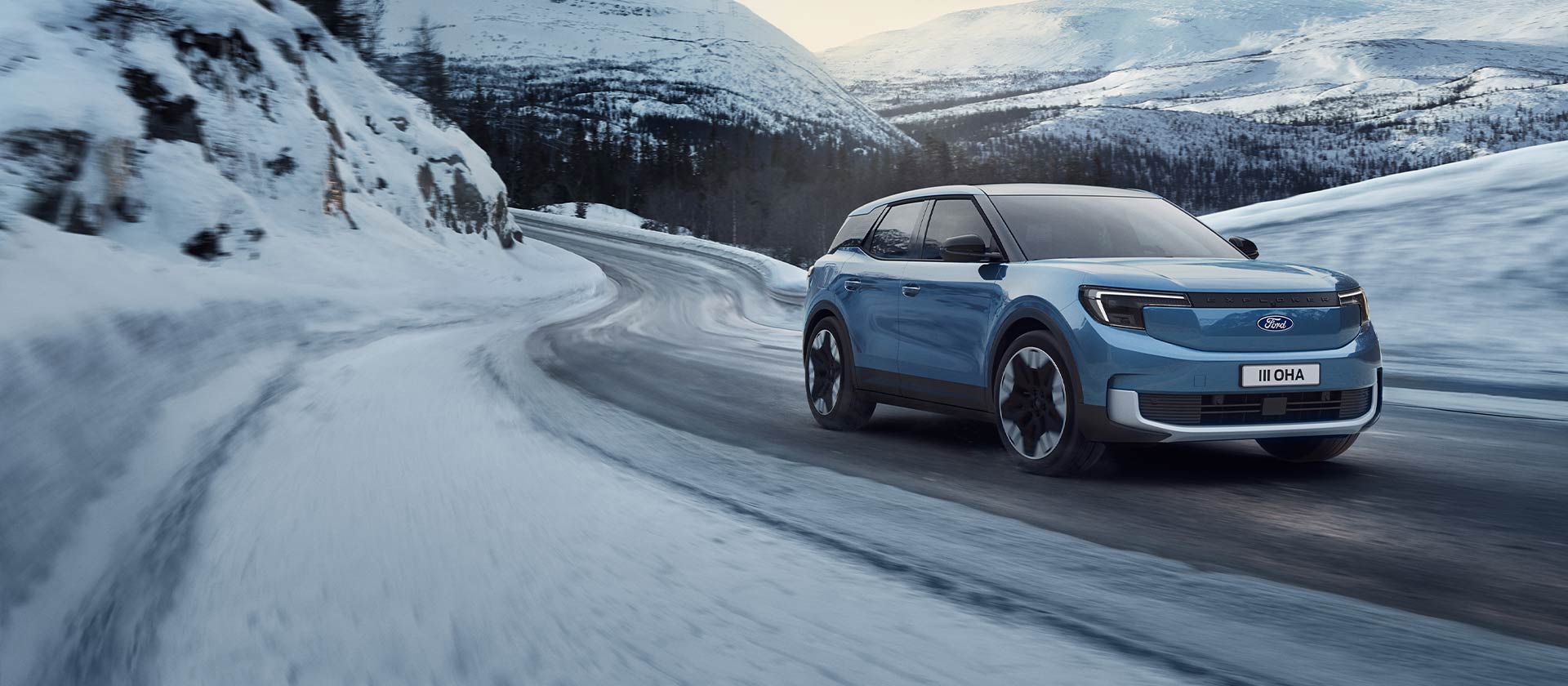 Ford Explorer blu-elettrico su una strada di montagna innevata, per evidenziarne la capacità e l'autonomia in condizioni invernali.