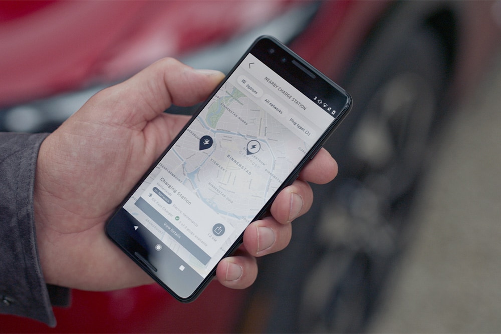 Uno smartphone che visualizza l'app FordPass™ con i punti di ricarica vicini per la ricarica pubblica di Ford EV.