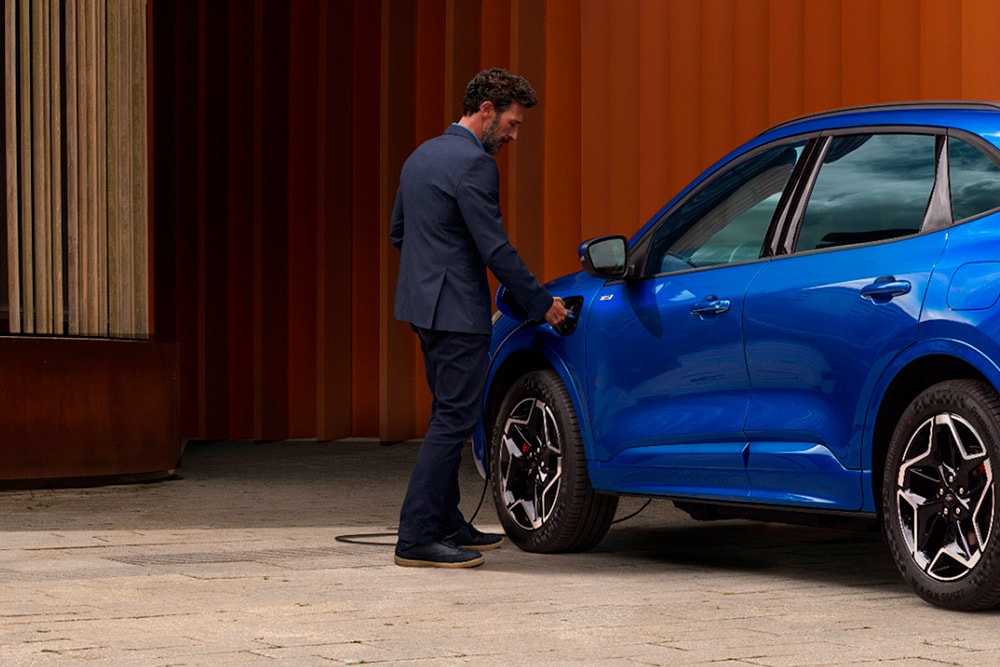 Una persona che collega un cavo di ricarica domestica EV a un'auto Plug-In Hybrid Ford.
