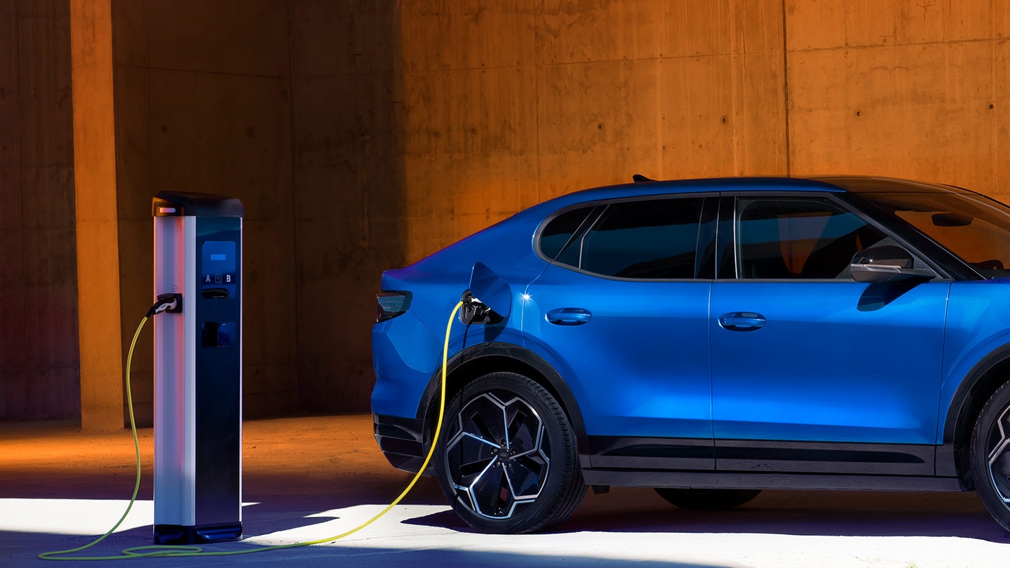 Un veicolo elettrico Ford Capri blu collegato a un caricatore EV.