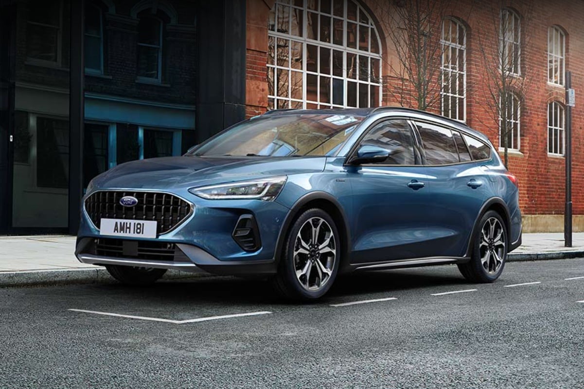 A blue Ford Focus hatchback parked on a cobbled city street.