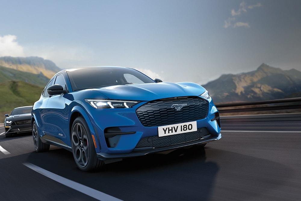 A blue Ford Mustang Mach-E driving down a highway.