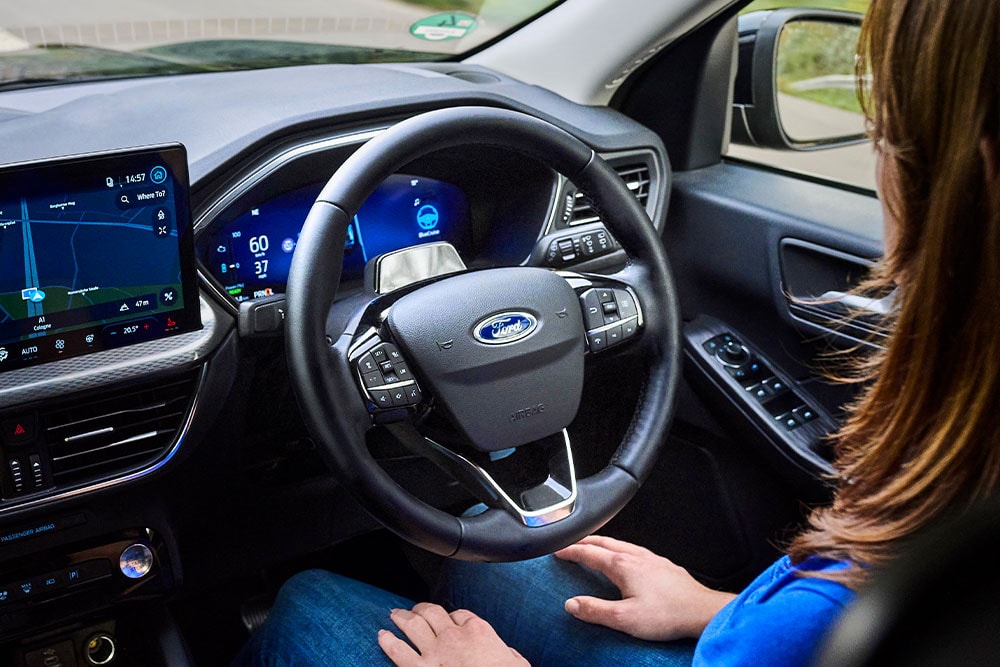 A man sitting in the Ford Mustang Mach-E with his hands away from the steering wheel, showing the BlueCruise technology.