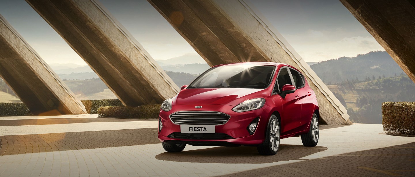 Ford Fiesta Titanium rossa parcheggiata sotto a dei pilastri Ford Fiesta Titanium rossa parcheggiata sotto a dei pilastri
