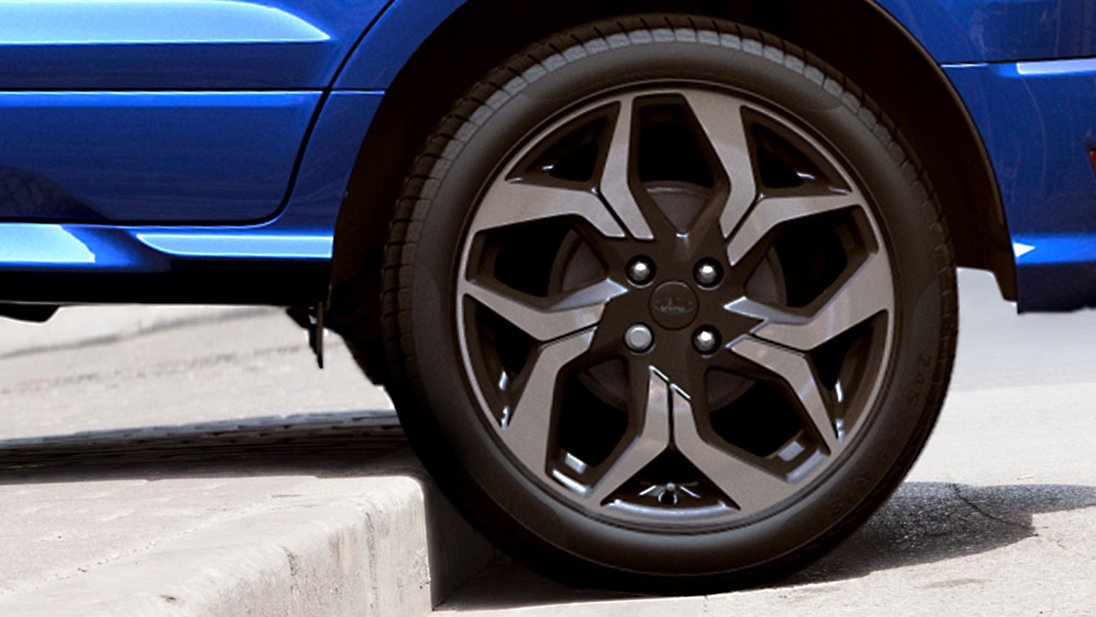Ford EcoSport blu con ruota posteriore che sale sul gradino alto di un marciapiede 