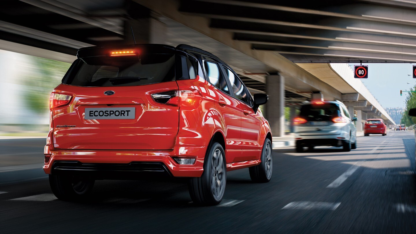 Ford EcoSport rossa vista da dietro che viaggia in direzione di un segnale stradale
