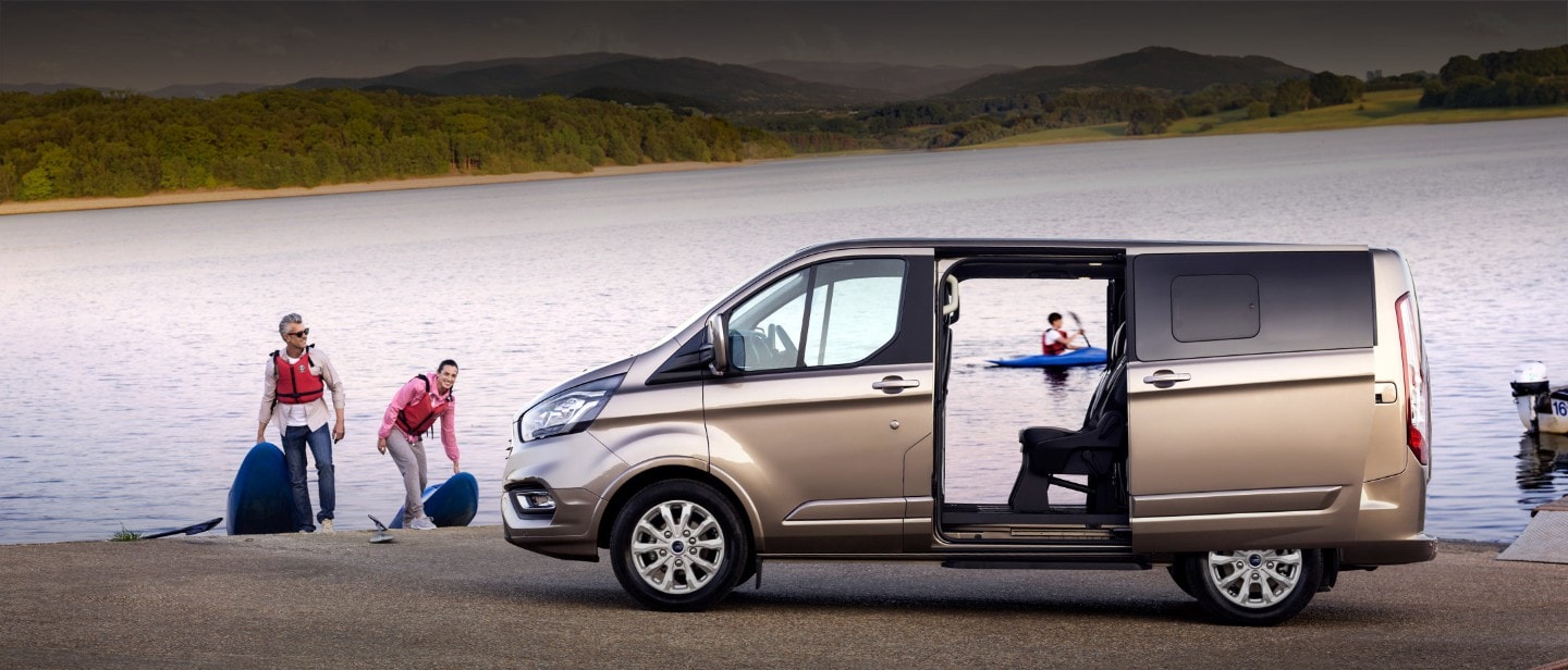 Ford Tourneo Custom parked by lake with side door wide open and people with kayaks