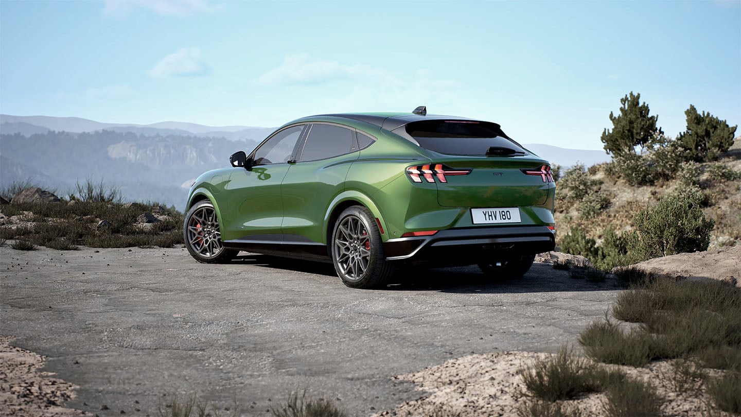 Vista posteriore del Ford Mustang Mach-E in Eruption Green parcheggiato su una strada di montagna.