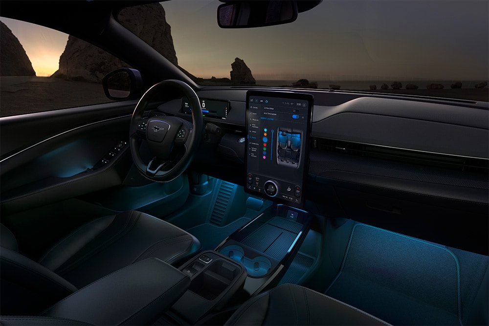 Interni del Ford Mustang Mach-E: il touchscreen SYNC 4 da 15,5" e illuminazione a LED ambientale impostata sul blu.