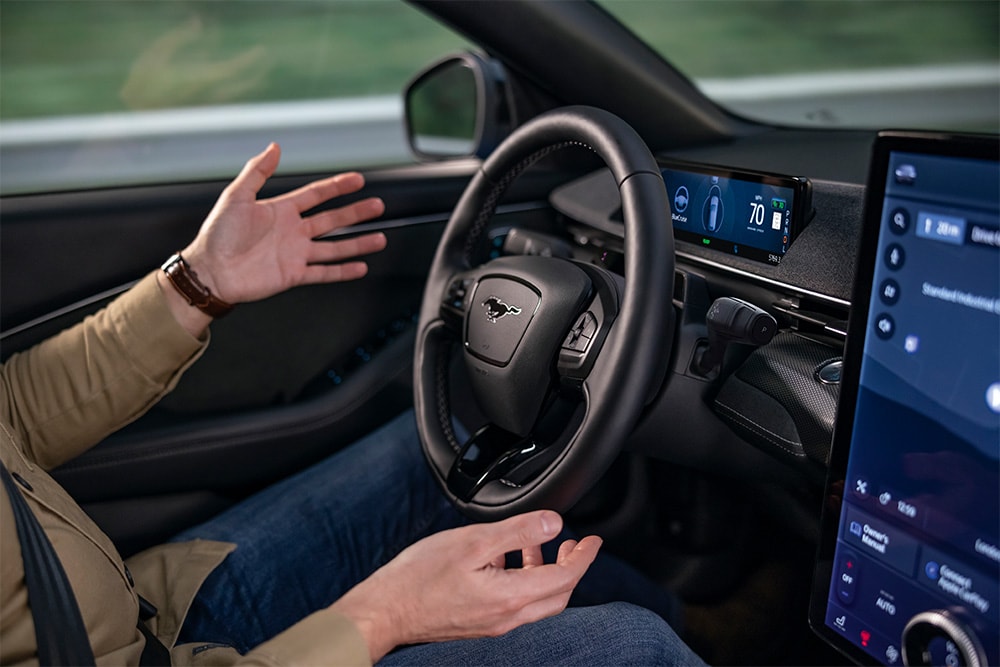 Due mani sollevate dal volante del Mustang Mach-E, a dimostrazione della tecnologia di guida autonoma BlueCruise