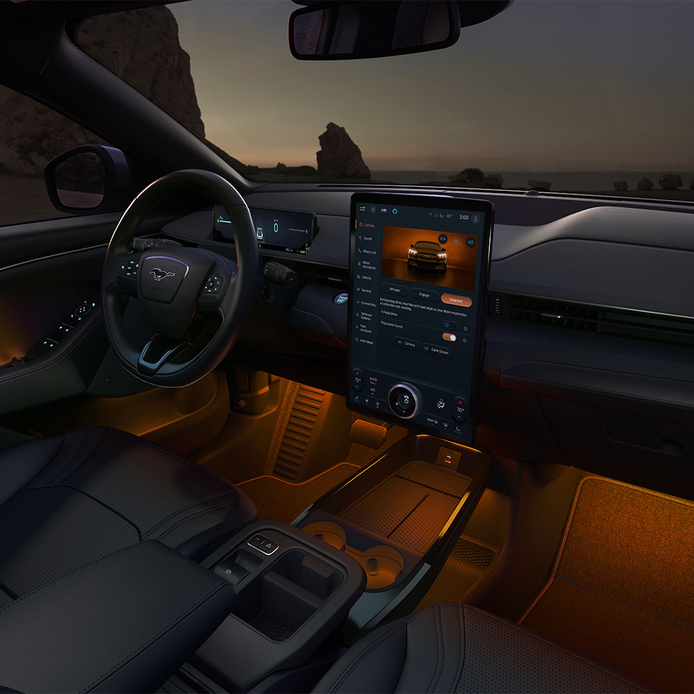 "Interni del Ford Mustang Mach-E: il touchscreen SYNC 4  da 15,5"" e l'illuminazione a LED ambientale impostata sull'arancione"