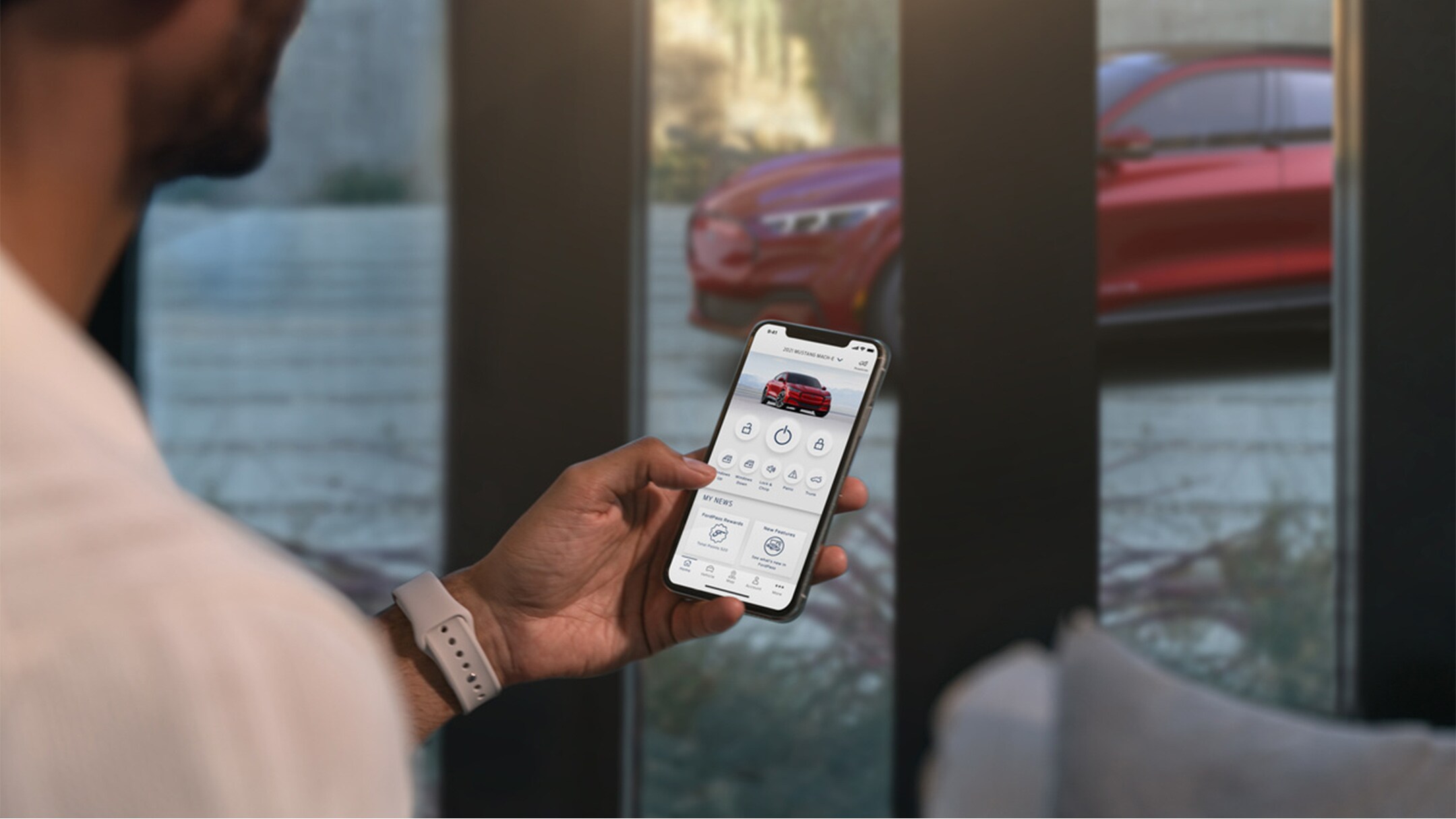 Un uomo che controlla le impostazioni della sua Ford Mustang Mach-E utilizzando le funzionalità di controllo da remoto del veicolo nell'app FordPass