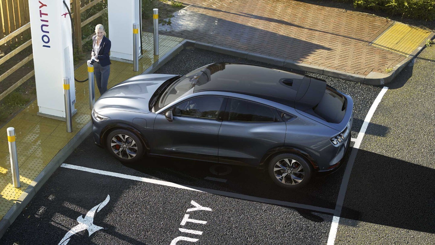 Una donna che ricarica Ford Mustang Mach-E presso una stazione di ricarica IONITY