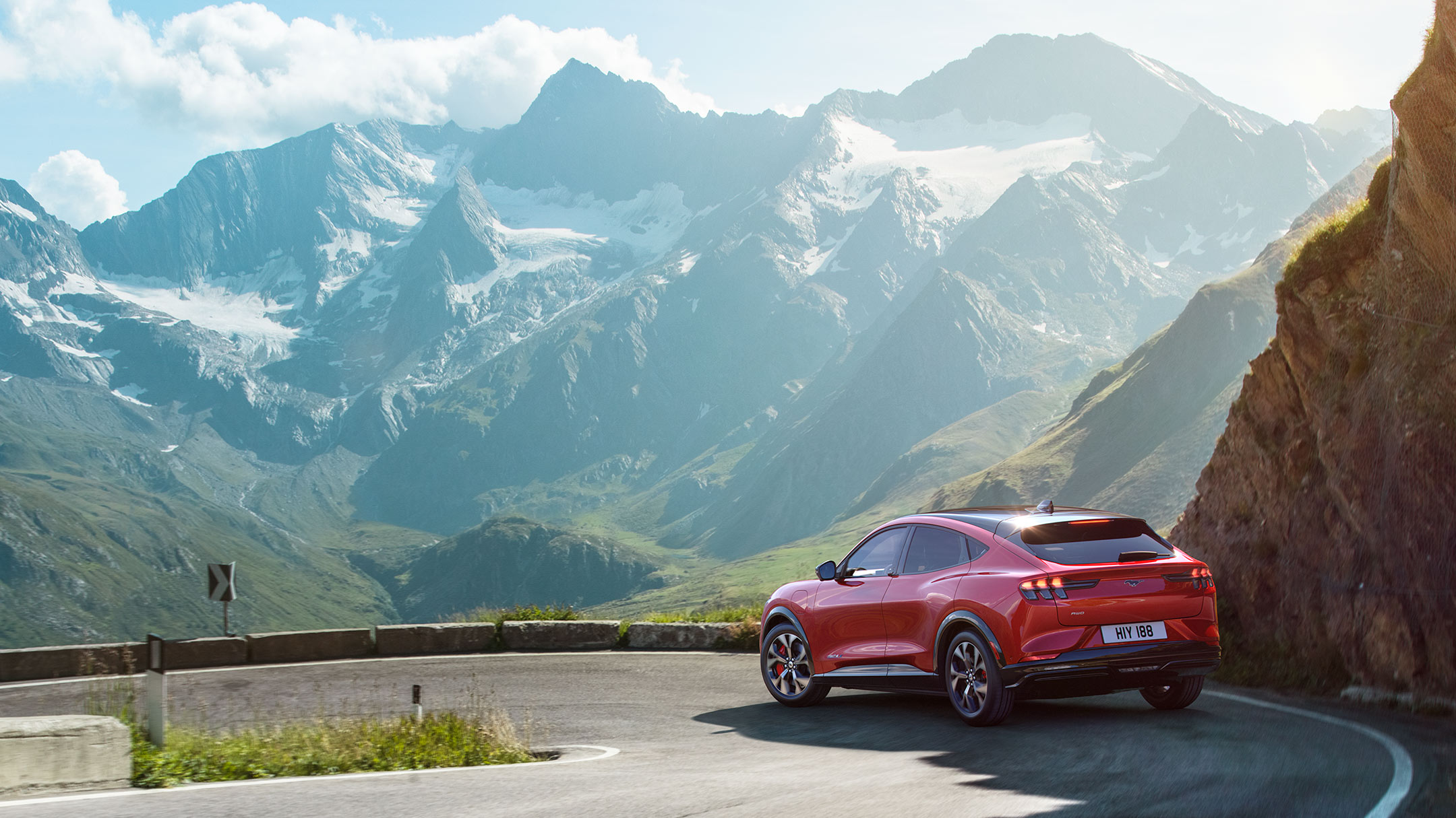 Ford Mustang Mach-E rossa in movimento su una strada tra le montagne