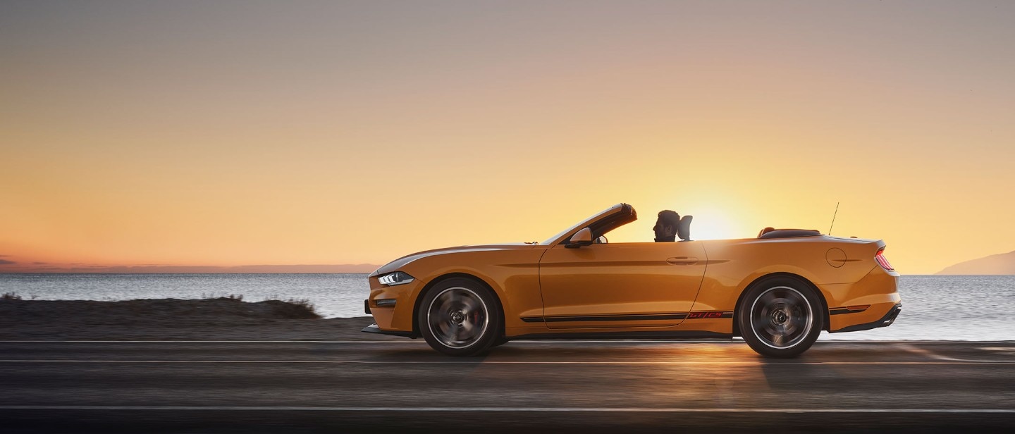 Ford Mustang California Edition driving down a highway against a sunset.