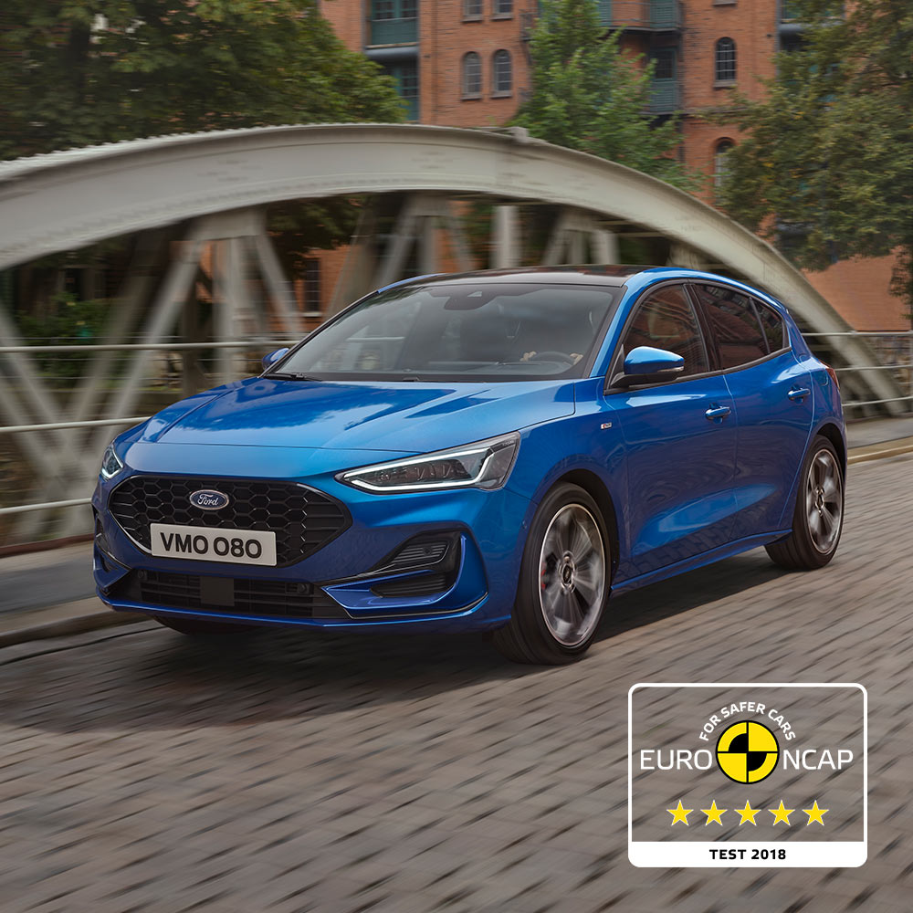 Una Ford Focus blu parcheggiata su un ponte, con il badge delle 5 stelle di valutazione sulla sicurezza Euro NCAP posizionato nell'angolo in basso a destra nell'immagine.