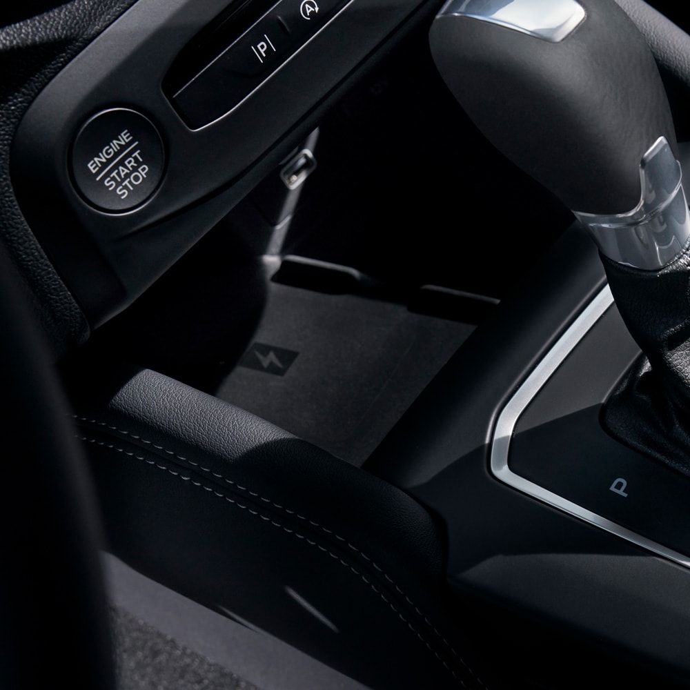 Un primo piano degli interni di una Ford Focus che mostra il caricabatterie wireless del telefono dietro il cambio.
