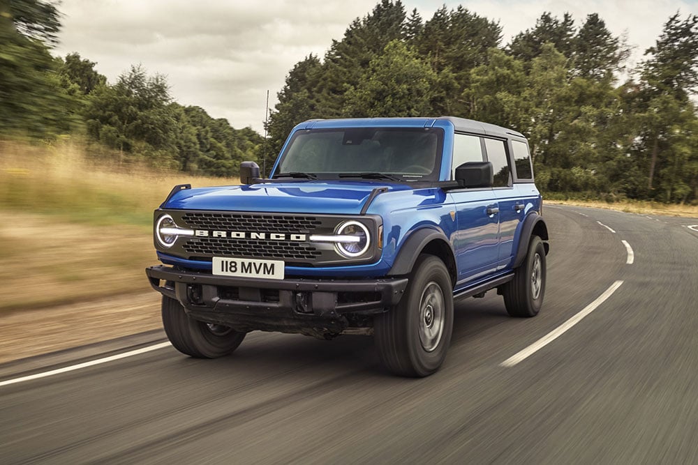 Vista frontale del nuovo Ford Bronco blu che percorre una strada di campagna.