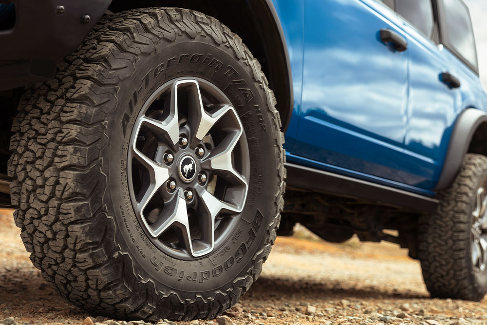 Primo piano degli pneumatici all-terrain di un Ford Bronco blu.