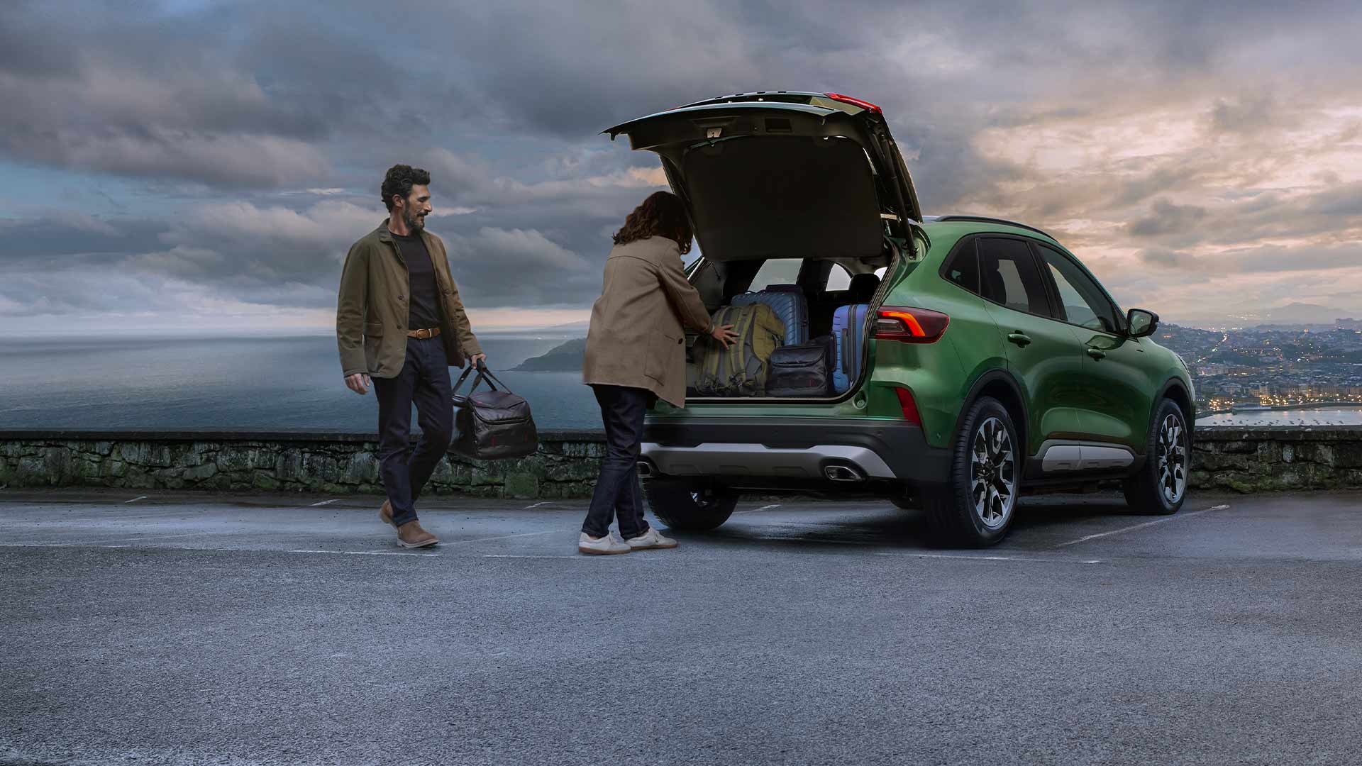 Due persone mentre caricano più valigie nello spazioso bagagliaio della Ford Kuga. 