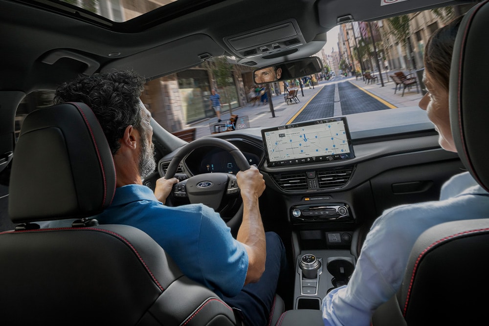 Due persone nella Ford Kuga mentre percorrono una strada cittadnellaa utilizzando le nelladicazioni sul display digitale da 12,3".