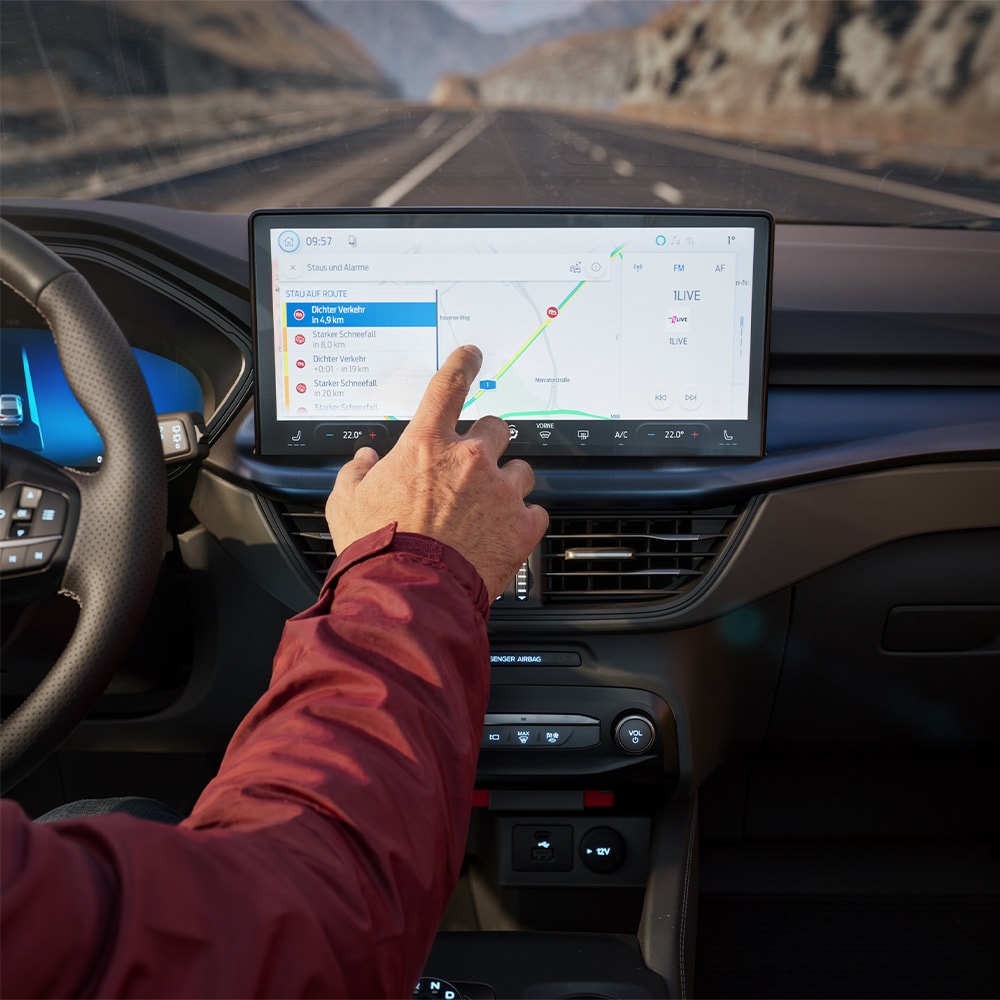 Un conducente usa la funzione di navigazione connessa sullo schermo digitale di un Ford Kuga BlueCruise Edition.