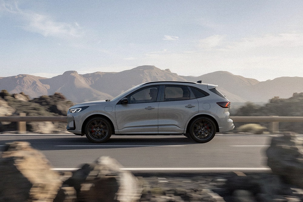 Una Ford Kuga color argento che percorre una suggestiva strada di montagna. 