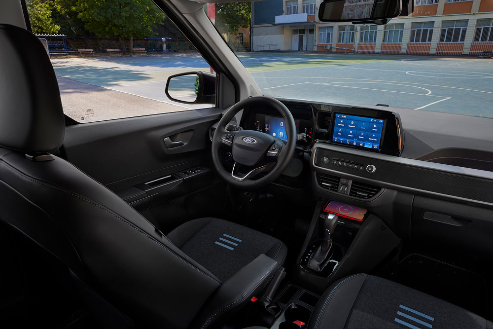 The interior of a Ford Tourneo Courier, showing the dashboard, steering wheel, infotainment screen, and front passenger seat.