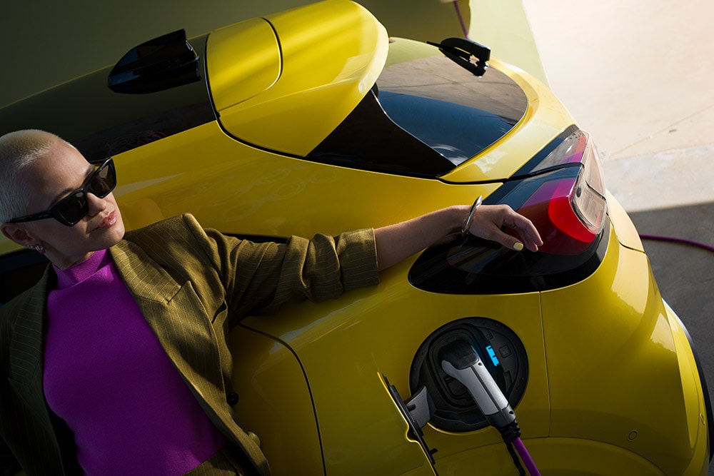 Ford Puma-e giallo in carica con una persona appoggiata all'auto