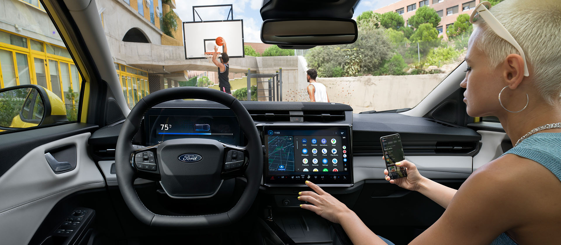 Interno del Ford Puma Gen-E® elettrico, con una persona che sincronizza wireless il cellulare con l'ampio schermo touchscreen.