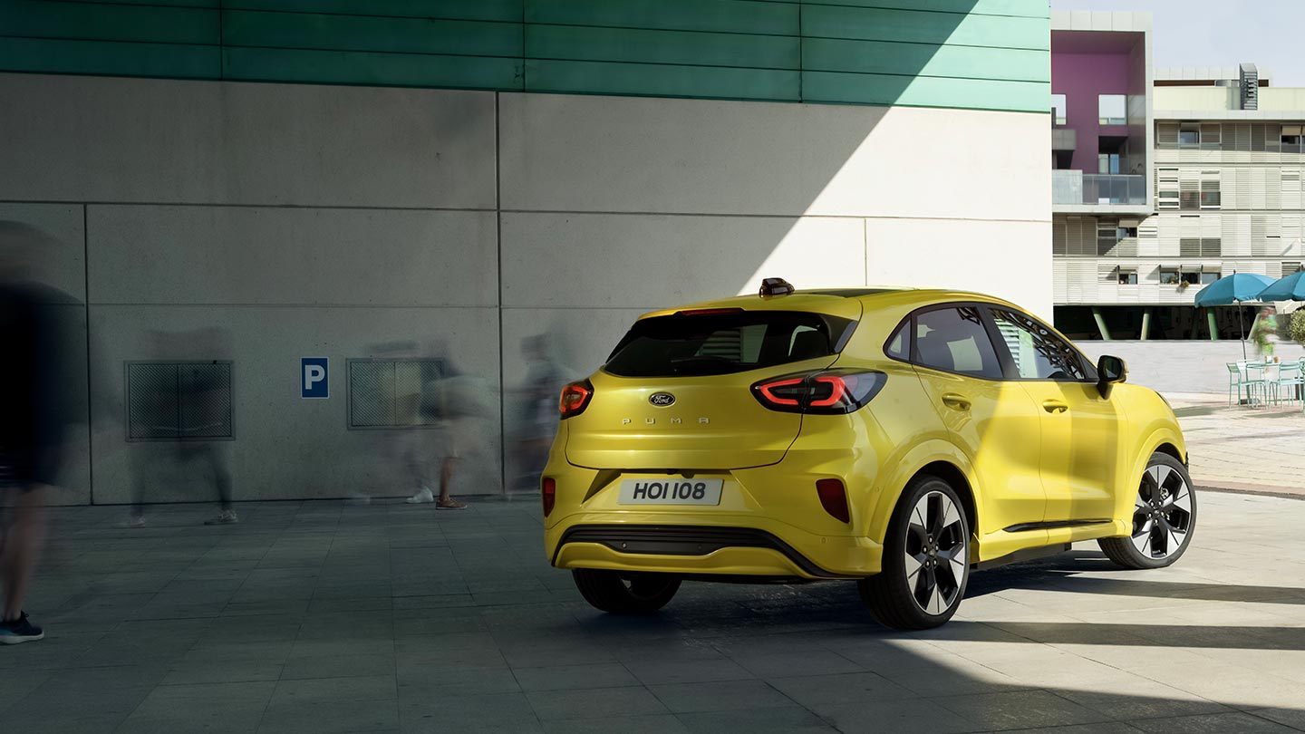 L'angolo posteriore di un Ford Puma Gen-E® elettrico giallo parcheggiato sotto un ponte.