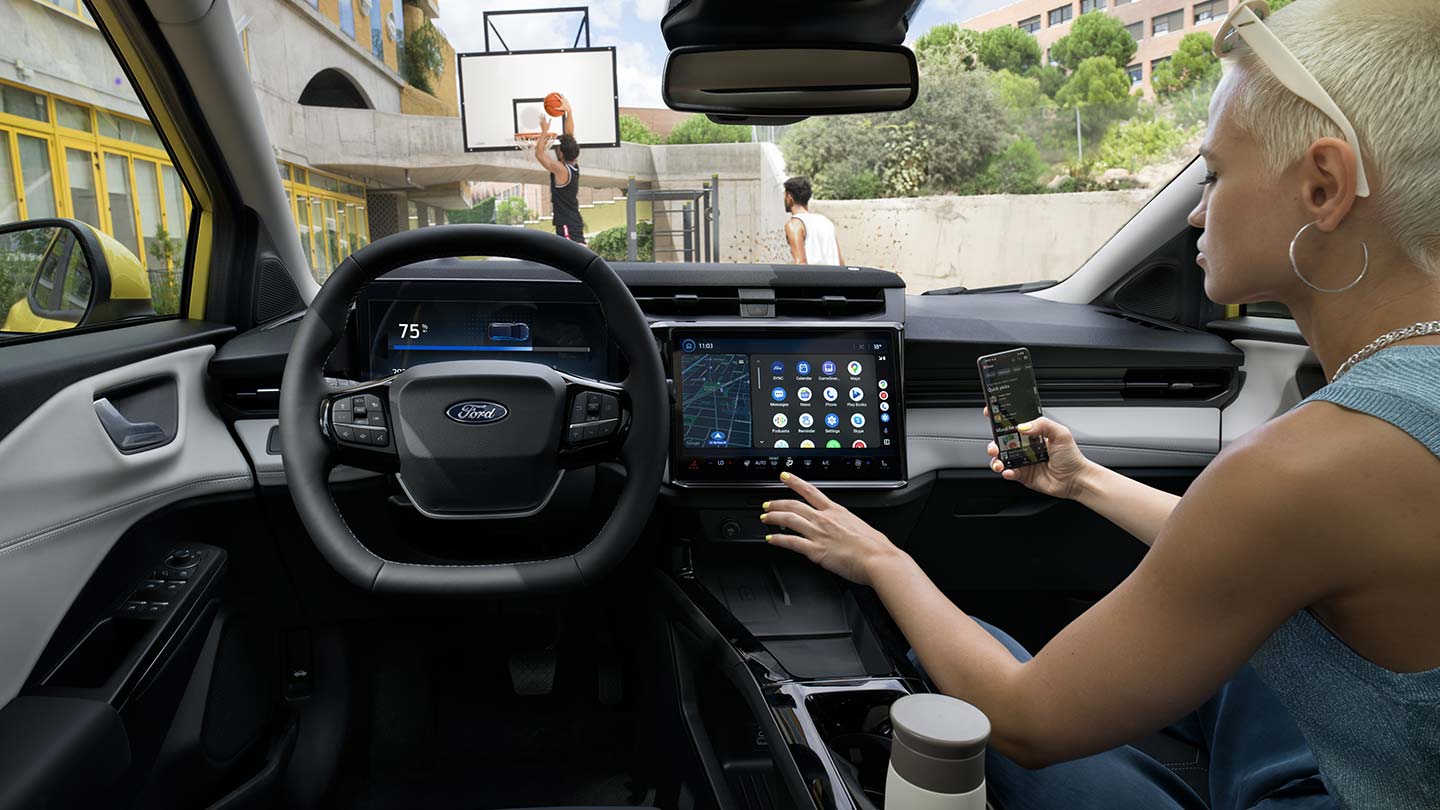 L'interno del Ford Puma Gen-E® elettrico, con una persona che sincronizza in modalità wireless il proprio cellulare con l'ampio schermo touchscreen.