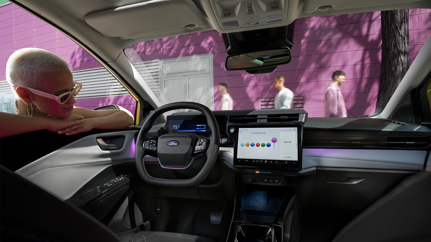 Persona che osserva gli interni del nuovo Ford Puma Gen-E®, con il grande touchscreen e l'illuminazione ambientale.