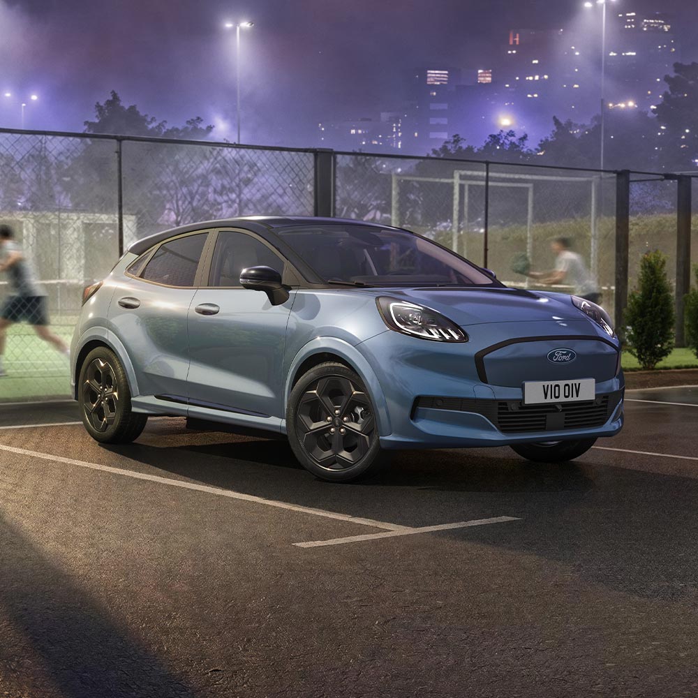 Ford Puma Gen-E Vapour Blue in edizione limitata con BlueCruise parcheggiato accanto a un campo da padel all'aperto.