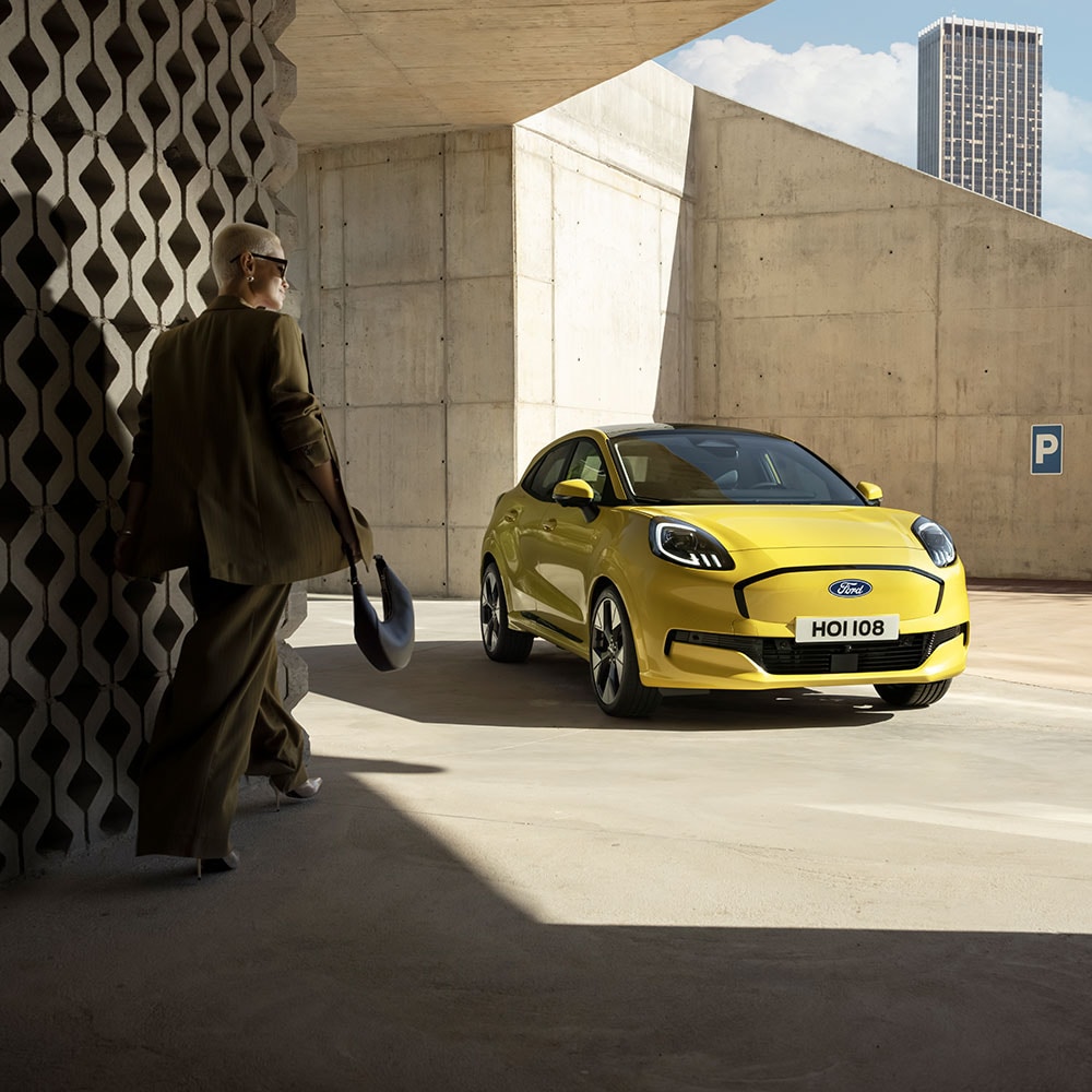 Una persona cammina verso il nuovo Ford Puma Gen-E® elettrico in giallo.
