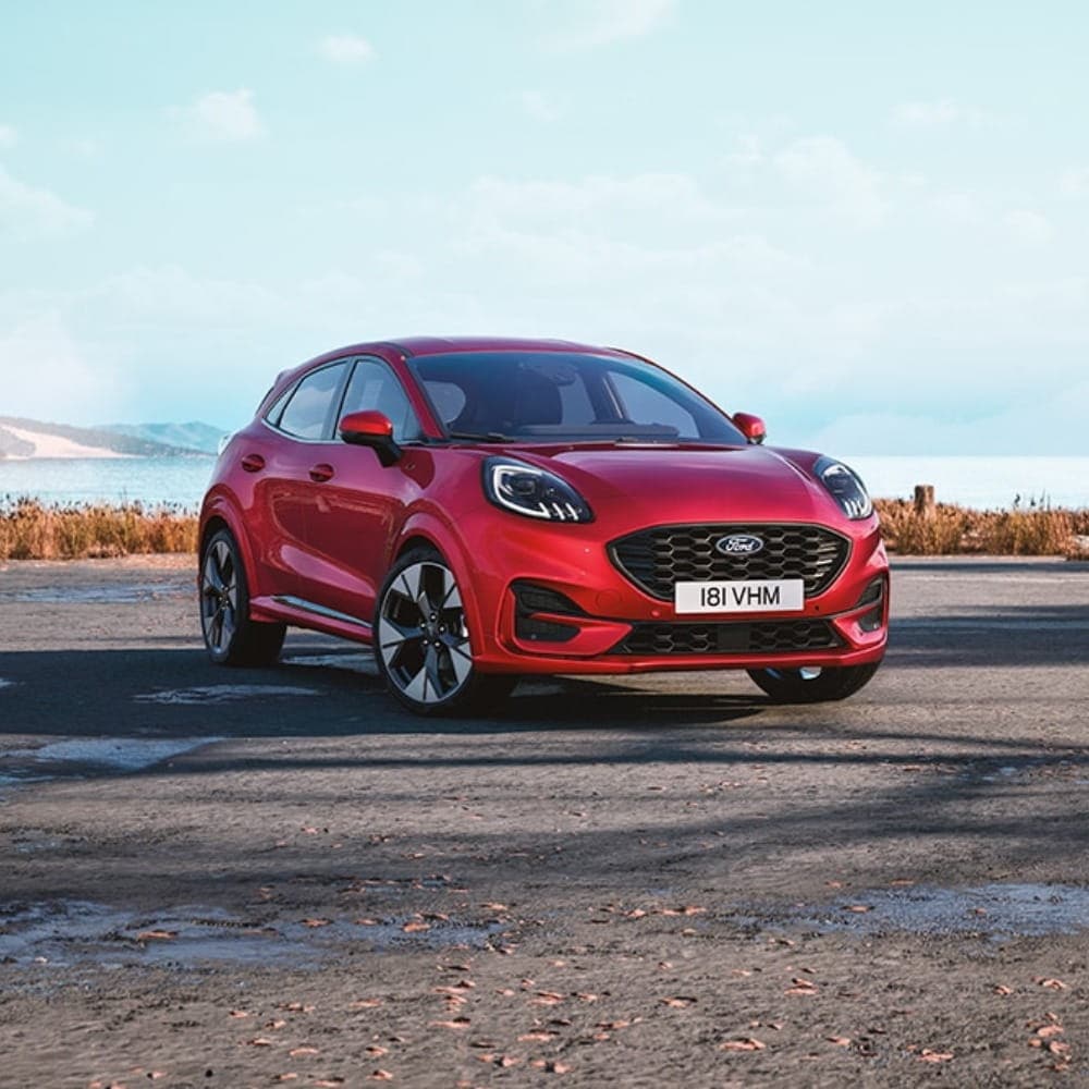 Puma rossa in primo piano parcheggiata.