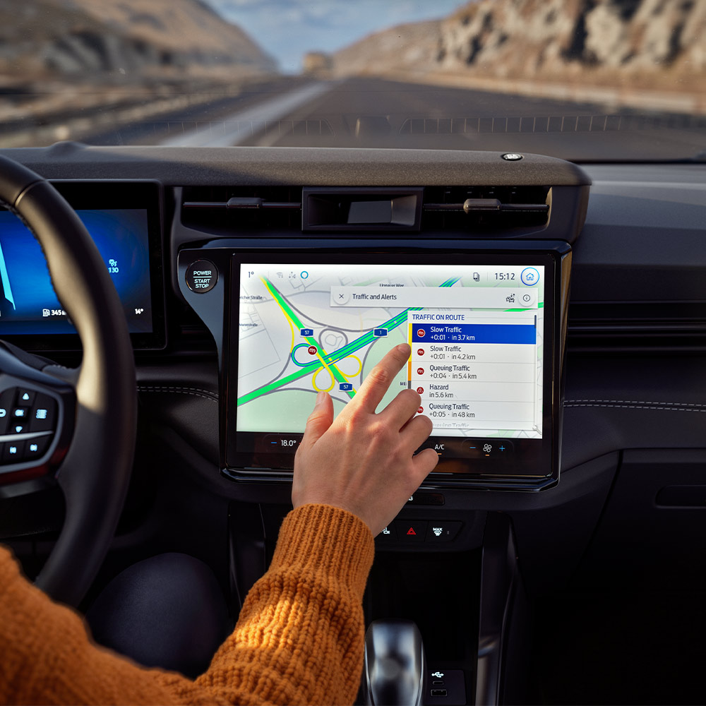 Un conducente usa la funzione di navigazione connessa sullo schermo digitale di un Ford Puma BlueCruise Edition.