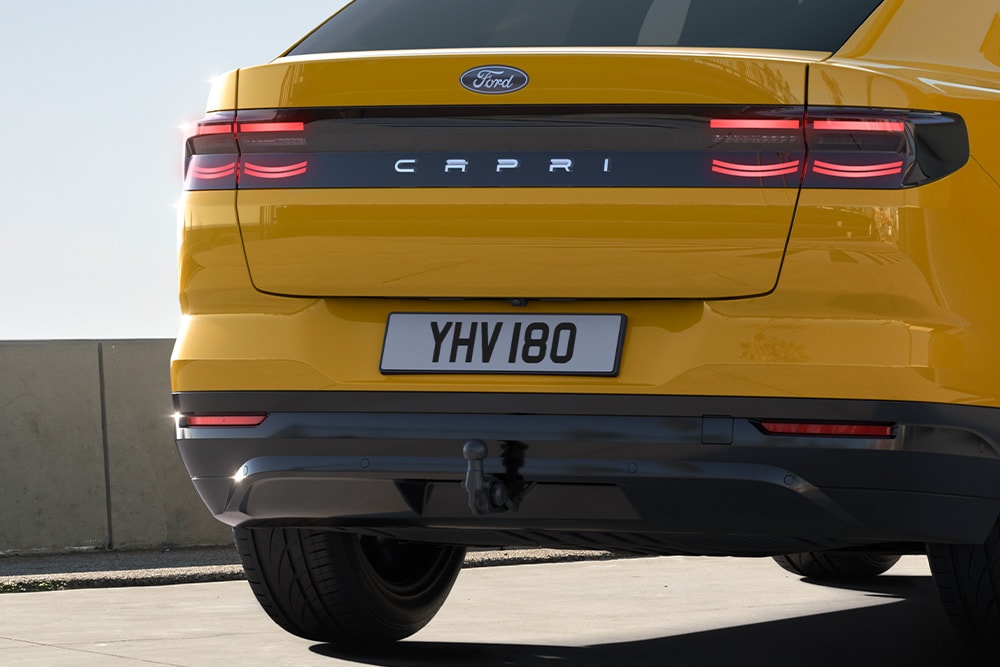 Vista posteriore di Ford Capri® giallo che percorre una strada urbana.