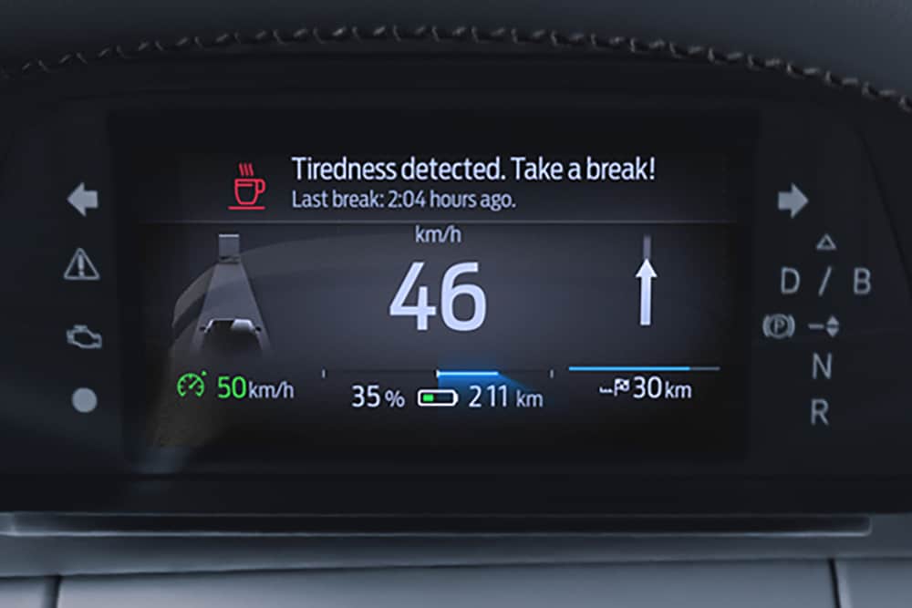The Ford Capri® instrument cluster displays the vehicle's speed and a Driver Alert warning message recommending a break.