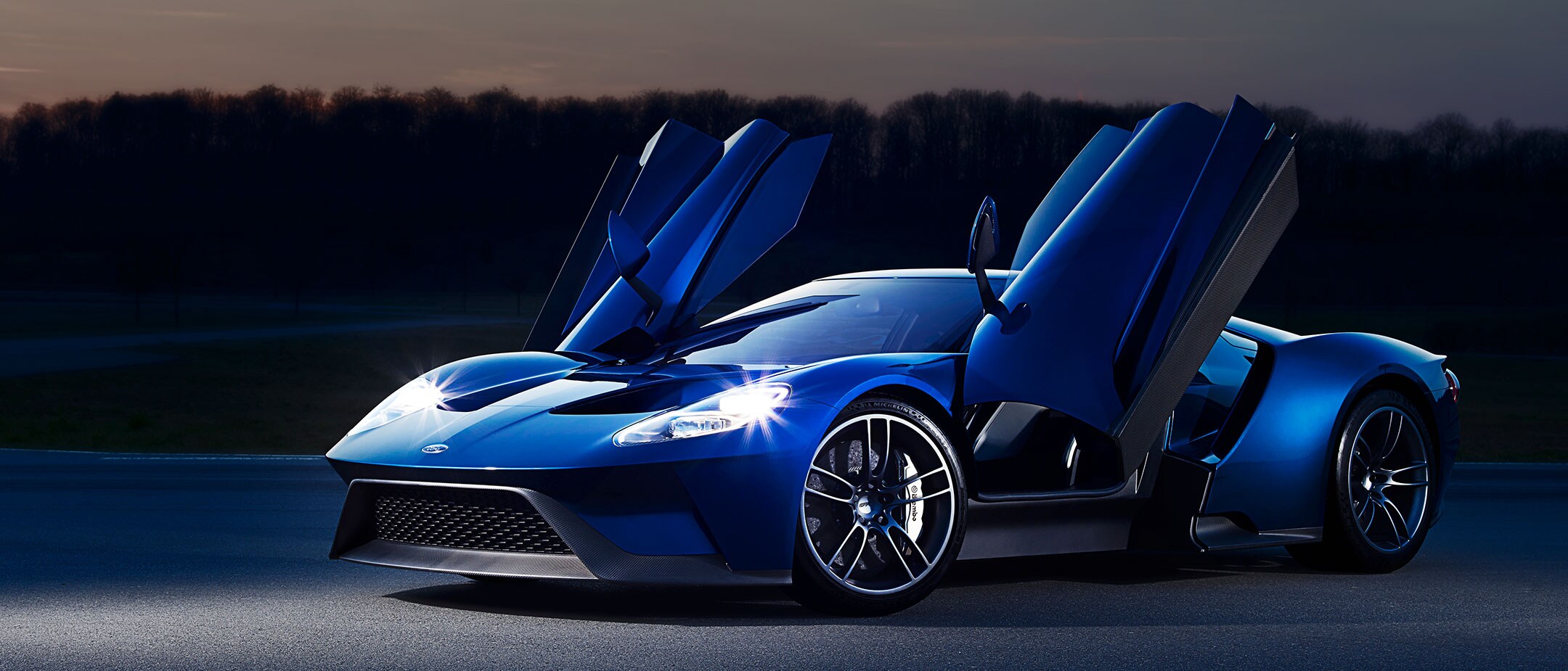 Ford GT con portiere aperte e fari accesi in contesto serale