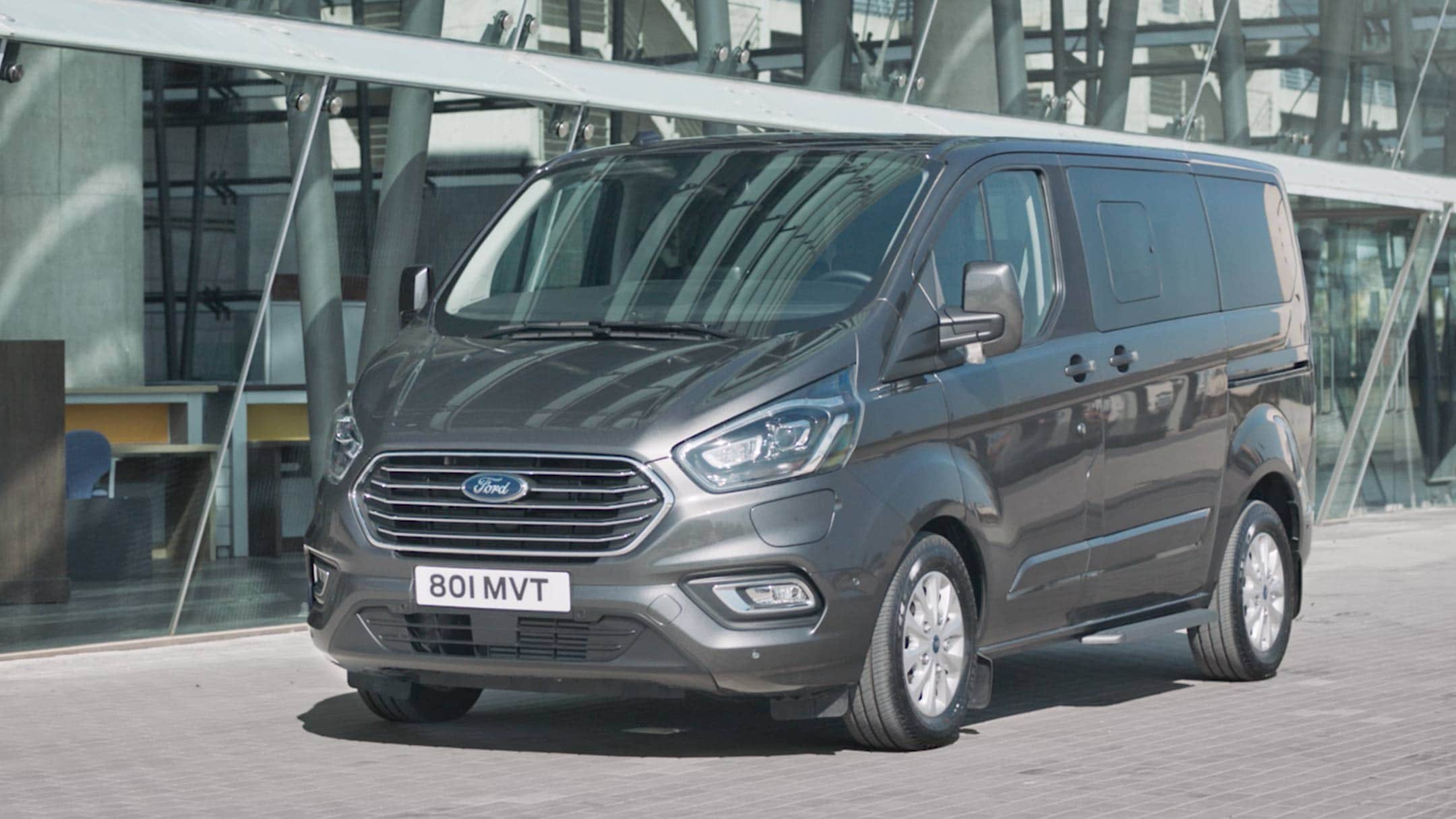 New Ford Tourneo Custom PHEV parked next to modern building