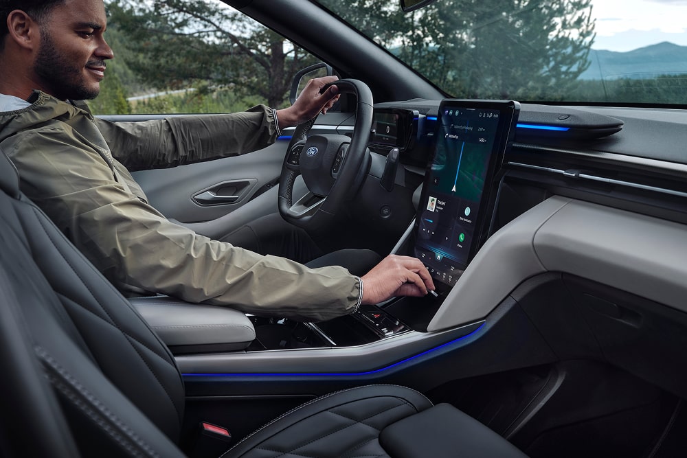Guidatore che usa il sistema infotainment su touchscreen all'interno di un SUV familiare Ford Explorer.